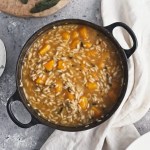 a butternut squash risotto in a black cast iron pan next to a beige napkin