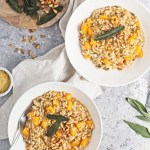 butternut squash risotto in white bowls on a marbled surface