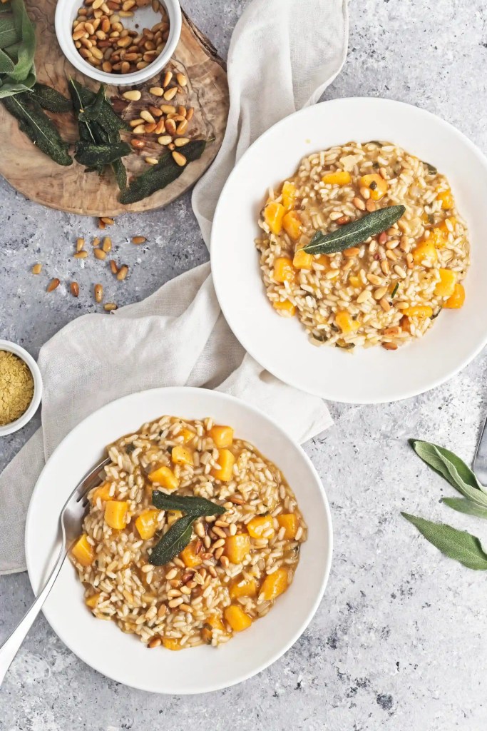 butternut squash risotto in white bowls on a marbled surface