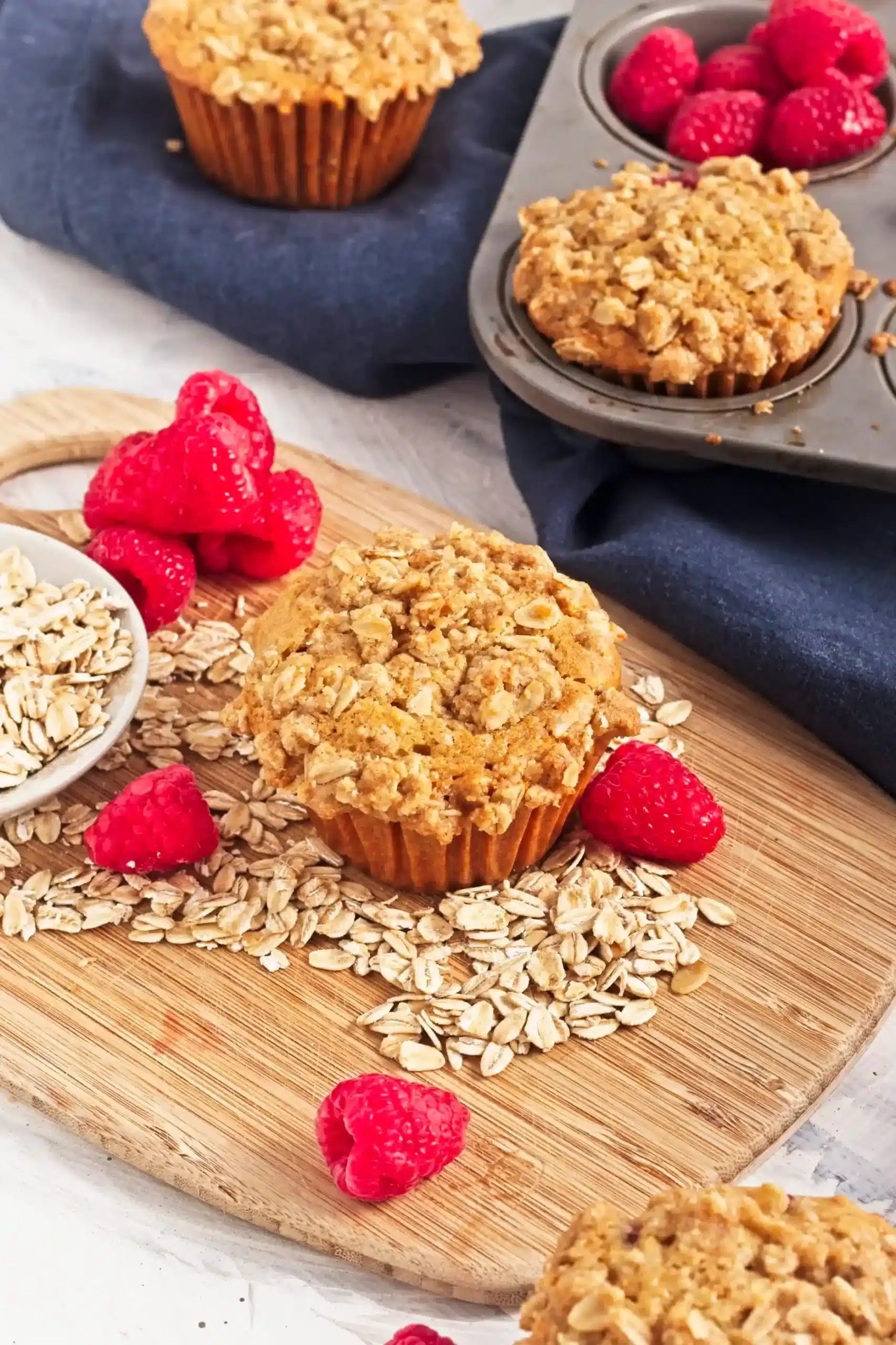 Vegan Raspberry Oat Muffins in a muffin tin with oats and raspberries around