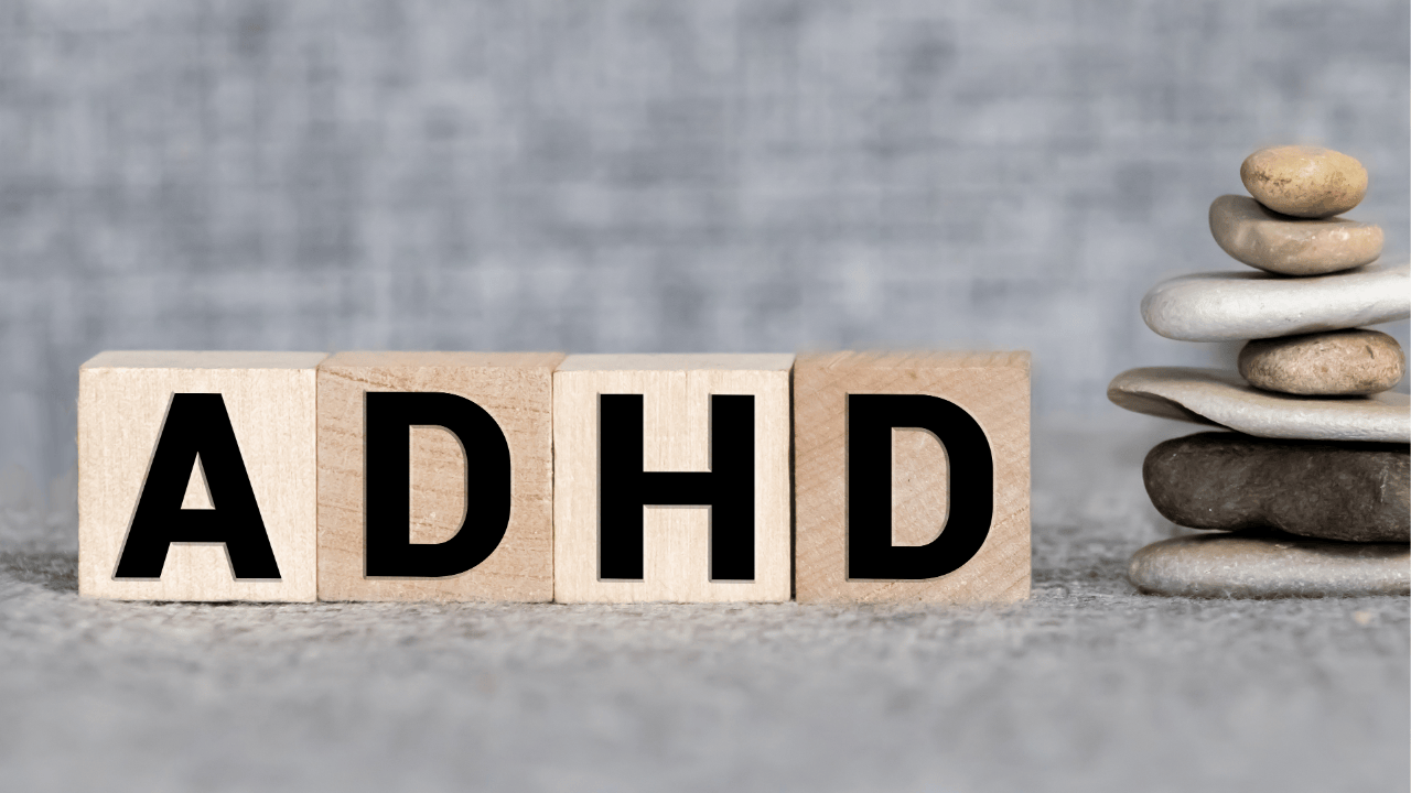 Wooden blocks spelling "ADHD" next to a stack of balanced stones, symbolizing the importance of seeking professional help to manage ADHD effectively. Learn how to find support, even on a budget, and improve your life with expert advice.