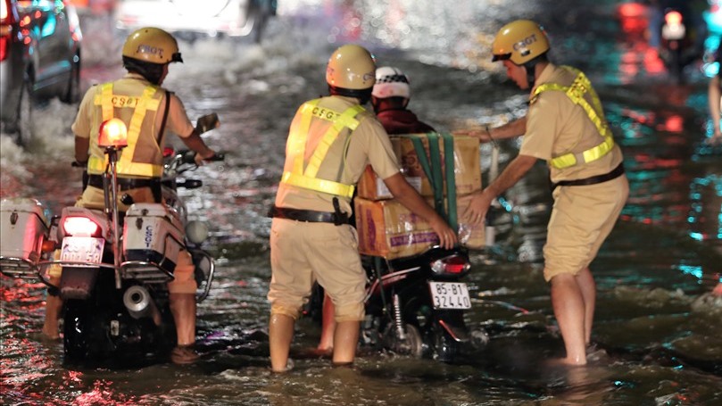 Traffic police in Hồ Chí Minh City help motorists navigate a flooded road. Illustrative photo: Trường Sơn/Báo Lao Động.