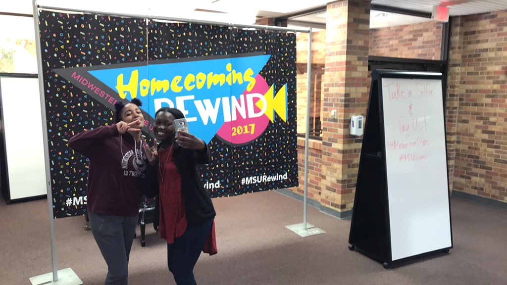 Zaquera Wallace, biology junior and Anissia Jones, exercise physiology junior, poses in front of the Homecoming banner in the Clark Student Center Atrium on Oct. 17. Photo by Avery Queen 