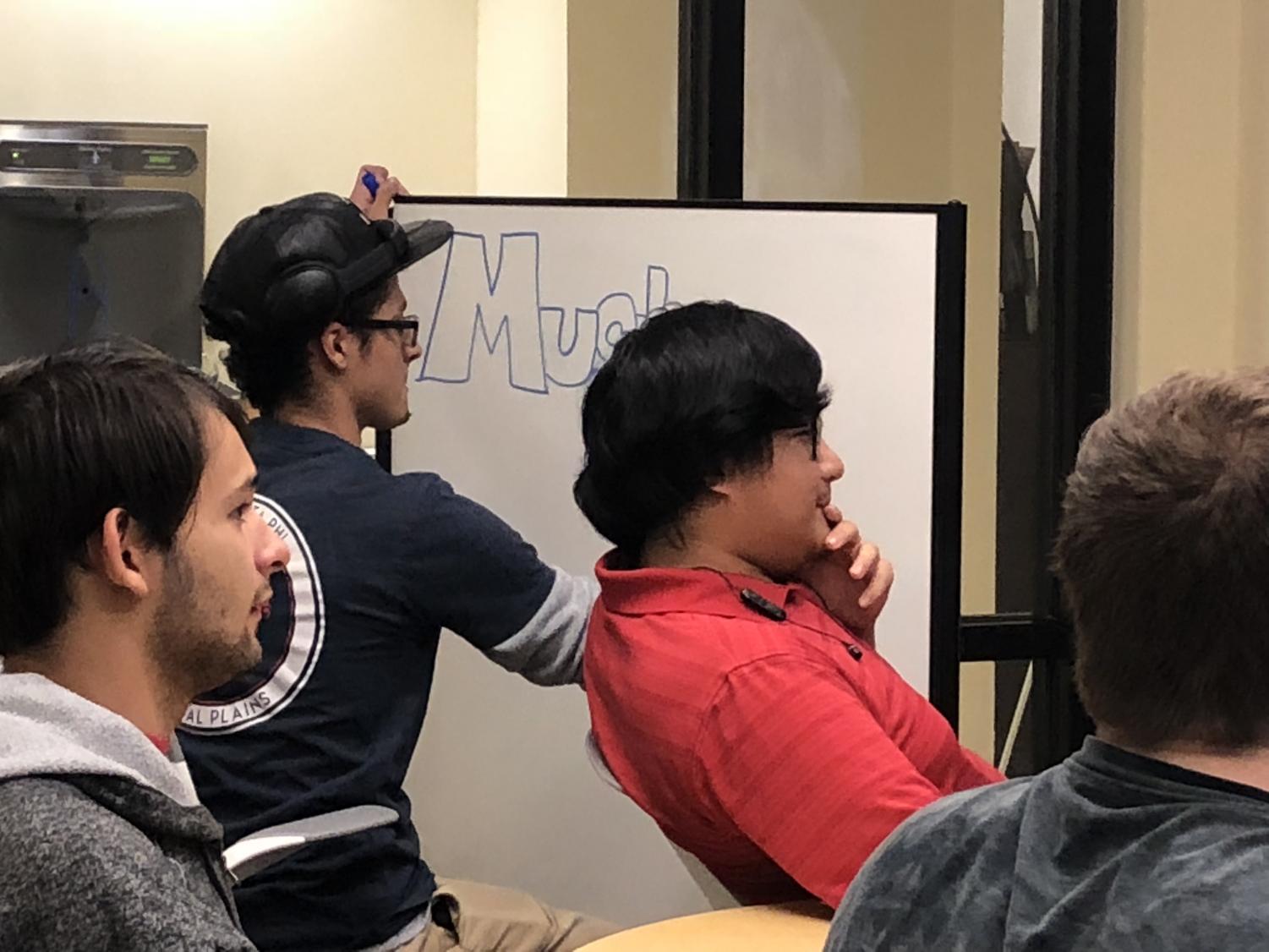 M.U.G. president and founder, Isaiah Edwards, writes the club's information on a white board to notify potential members of the club's meeting location.