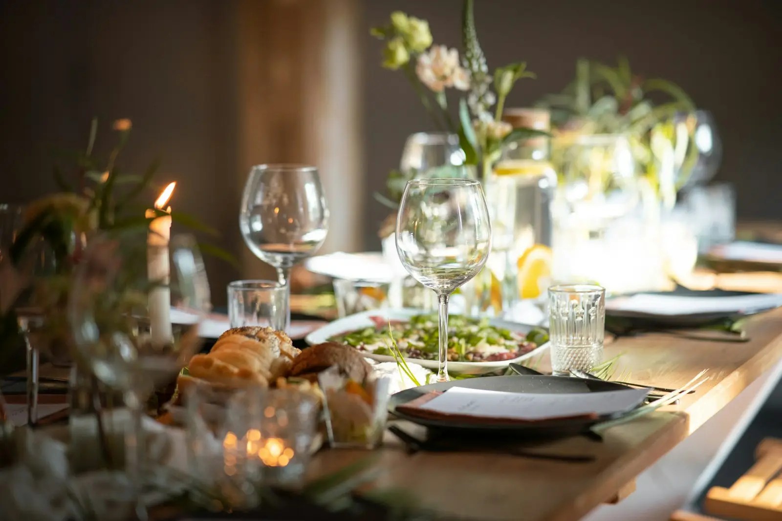 A candlelit table set for dinner with wine glasses and plates