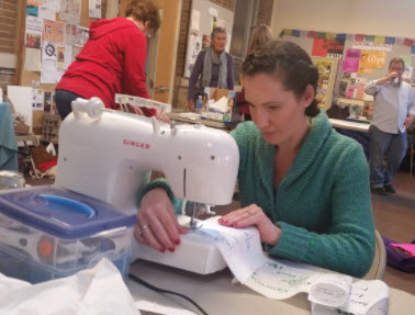 4. Stitchers first attach the fabric squares with pins, and then sew the left and right edges of your square with its neighboring squares. This process creates creating long rows of 8 squares.