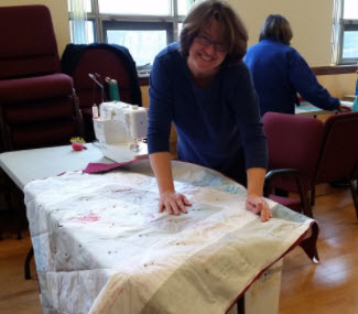 8b. Batting is sandwiched between the quilt top and a fabric backing. Safety pins are used to temporarily tack the three layers together.
