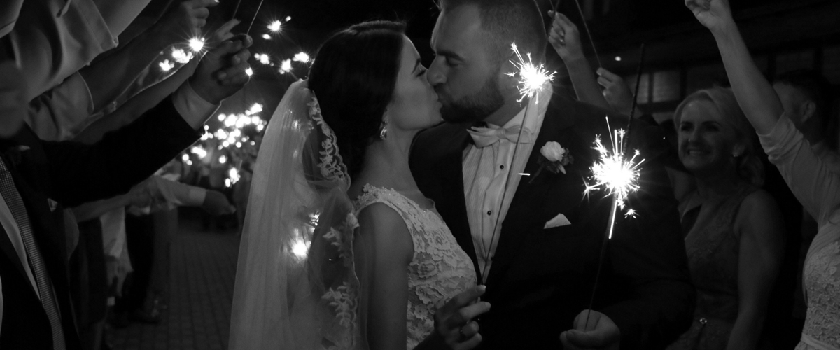 Bride and groom sharing a kiss with sparklers at night.