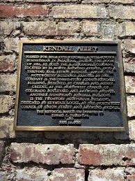 Historical plaque on the brick wall marking Kendall Alley in Pasadena, California, describing its significance and original developer.