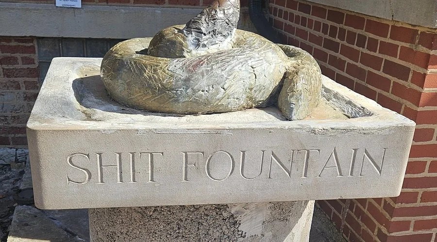 Close-up of Shit Fountain Chicago bronze dog-poop sculpture on a limestone pedestal