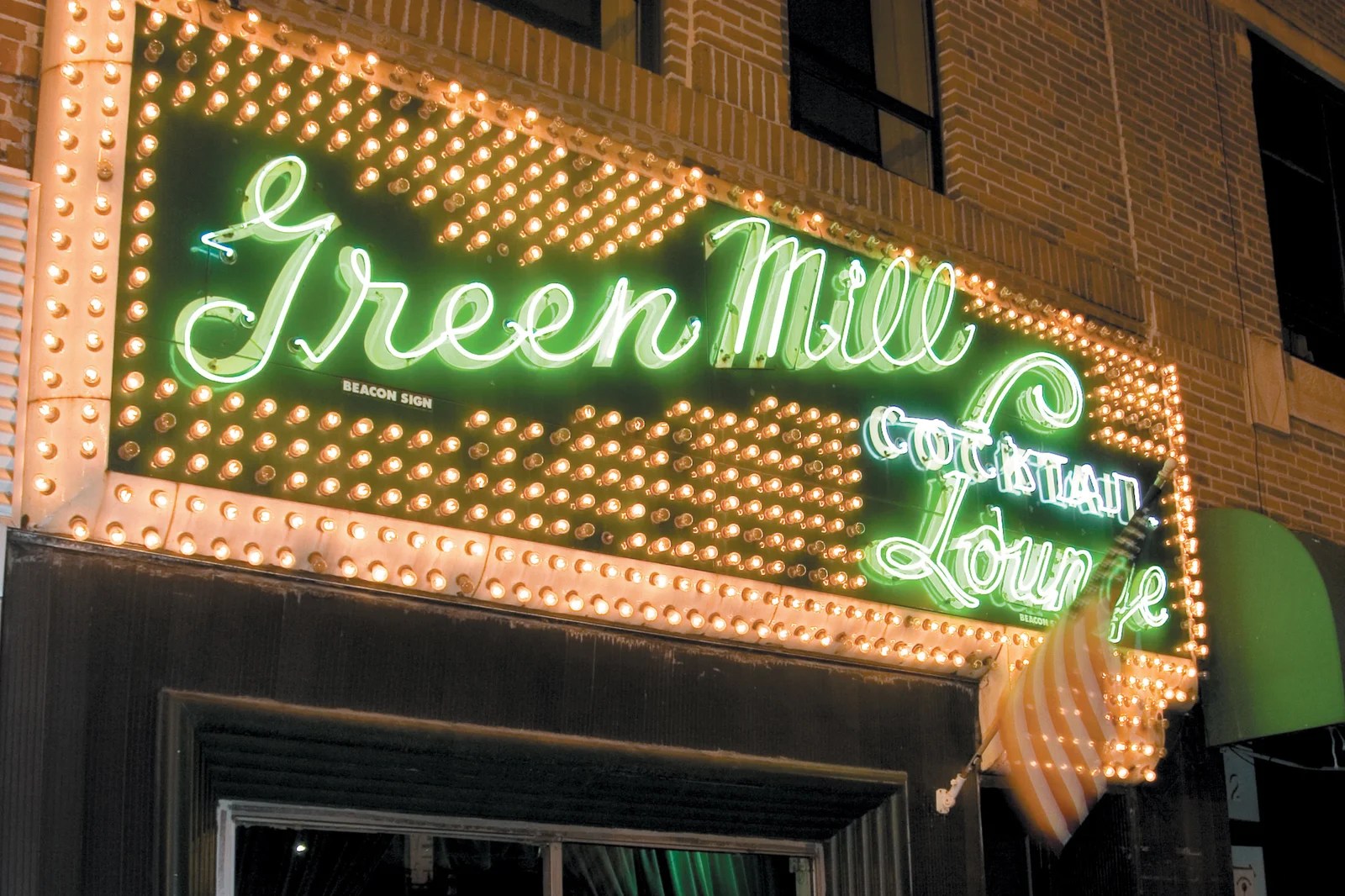 Exterior view of Green Mill Chicago neon sign glowing at night in Uptown.