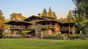 The Gamble House Pasadena historic landmark surrounded by green lawn and trees.