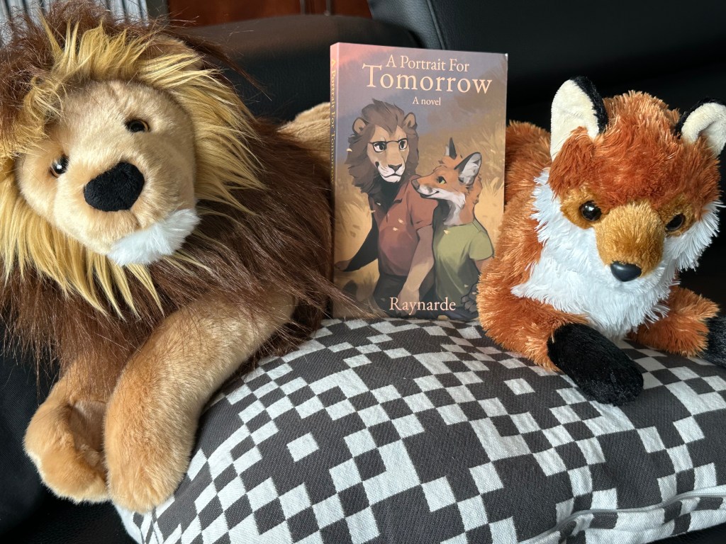 A photo of a copy of my book in between a stuffed toy lion and fox.