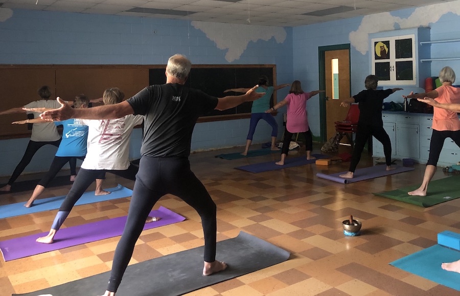 Many adults standing on mats in warrior pose