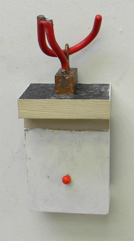 Painted wood, 3.5"x3.5"x7". Broken red hook passing through two eye screws with red glass ball pin.