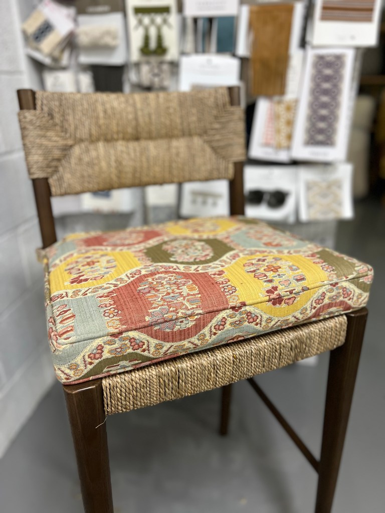 Made-to-measure seat cushion for a high top chair. Fabricated from a cottage core inspired fabric with a wavy banner running horizontally across the cushion. finish with a pattern matching self welt.