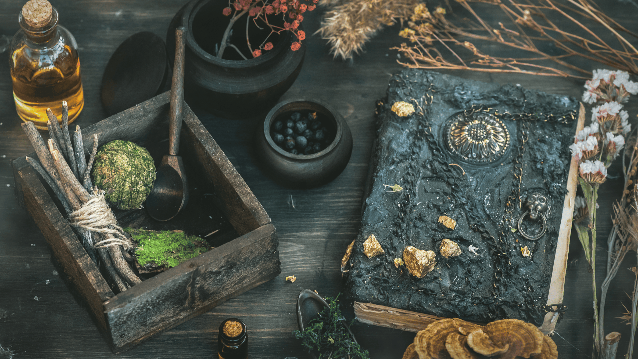 Magic supplies including a leather bound book, a box full of herbs, and flowers