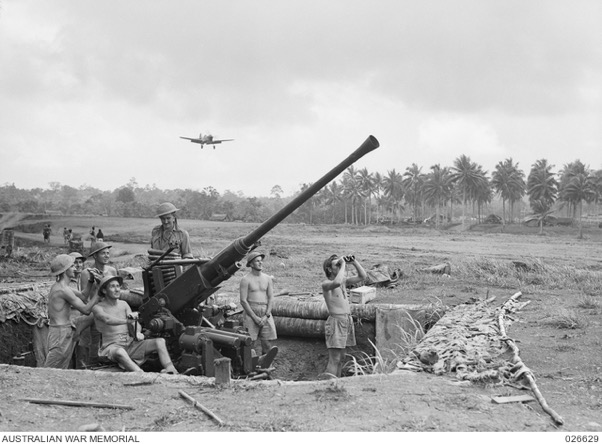 Milne Bay, Papua, September 1942: a Bofors gun position manned by the 2/9th Light Anti-Aircraft Battery, Royal Australian Artillery, at Gili-Gili airfield. In the background a Kittyhawk is about to land.