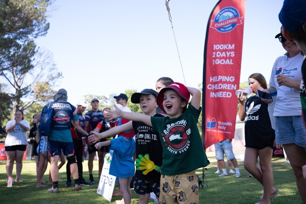 Some of the children and their families who are supported by the funds raised cheering at the finish line