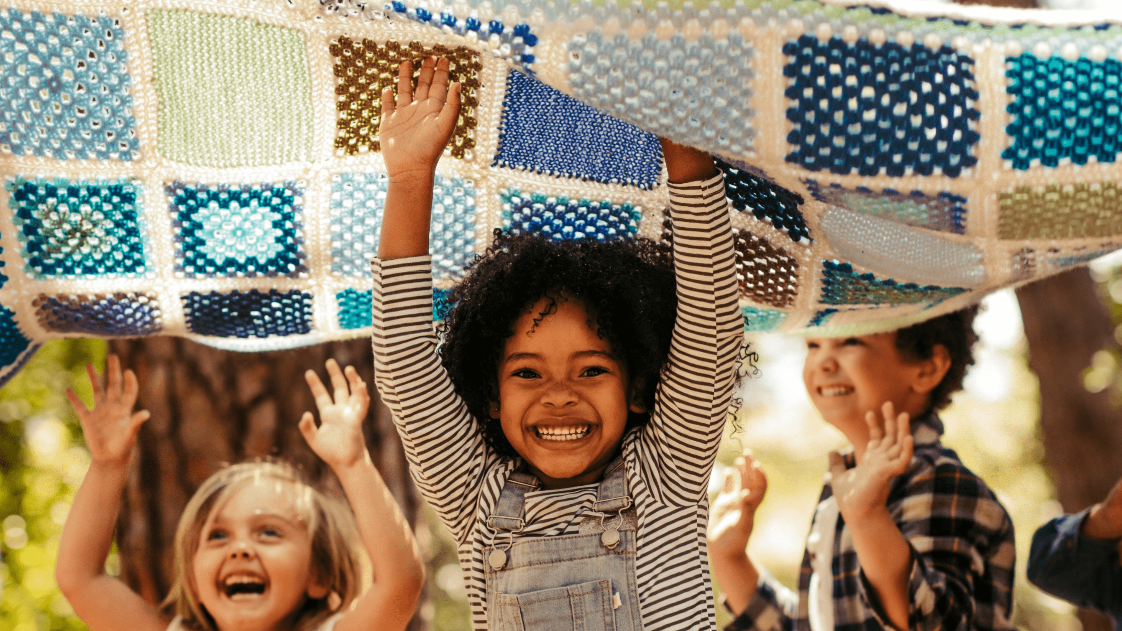 A group of children playing outdoors under a blanket