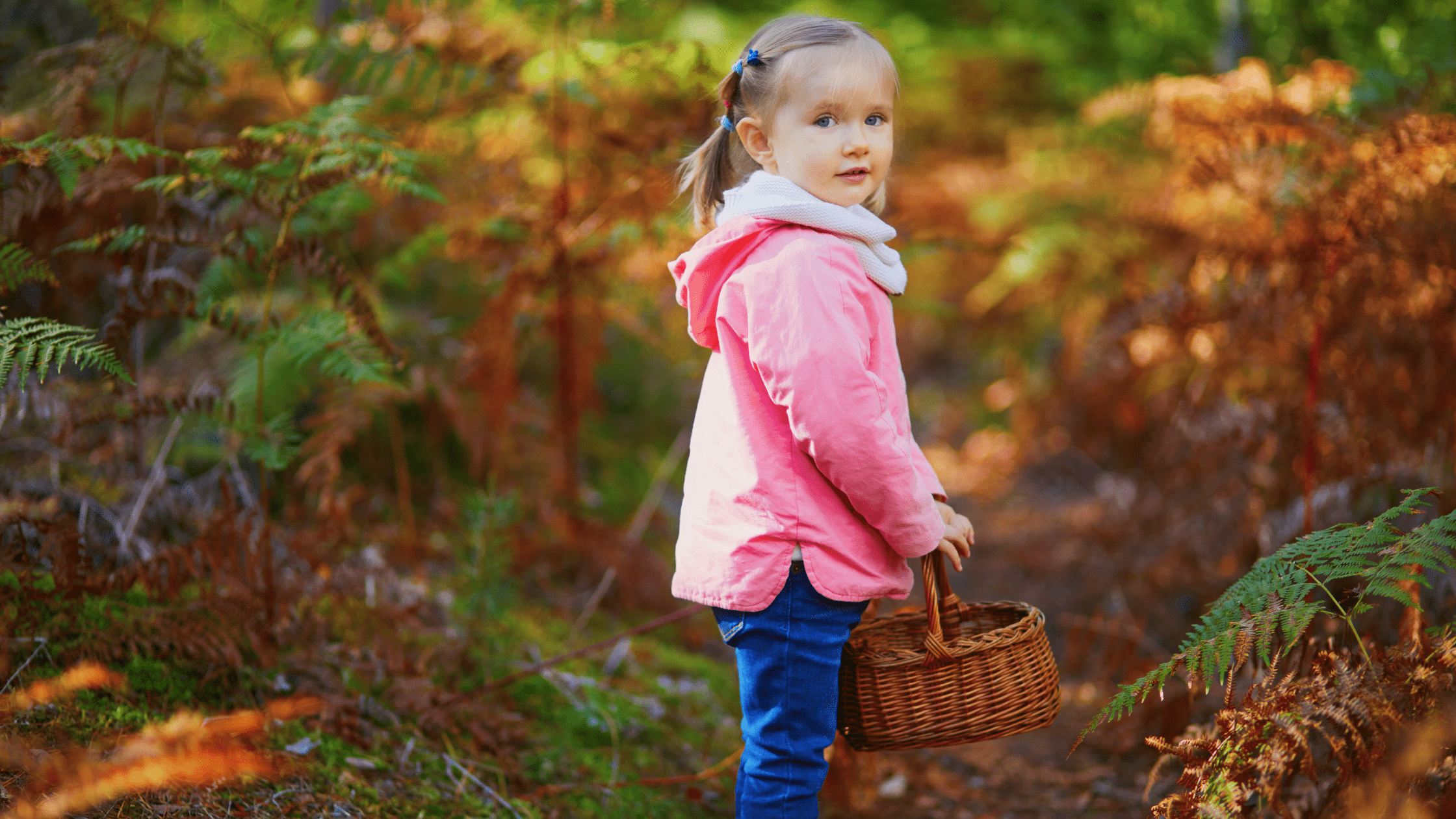 a little girl standing in a forest with a basket