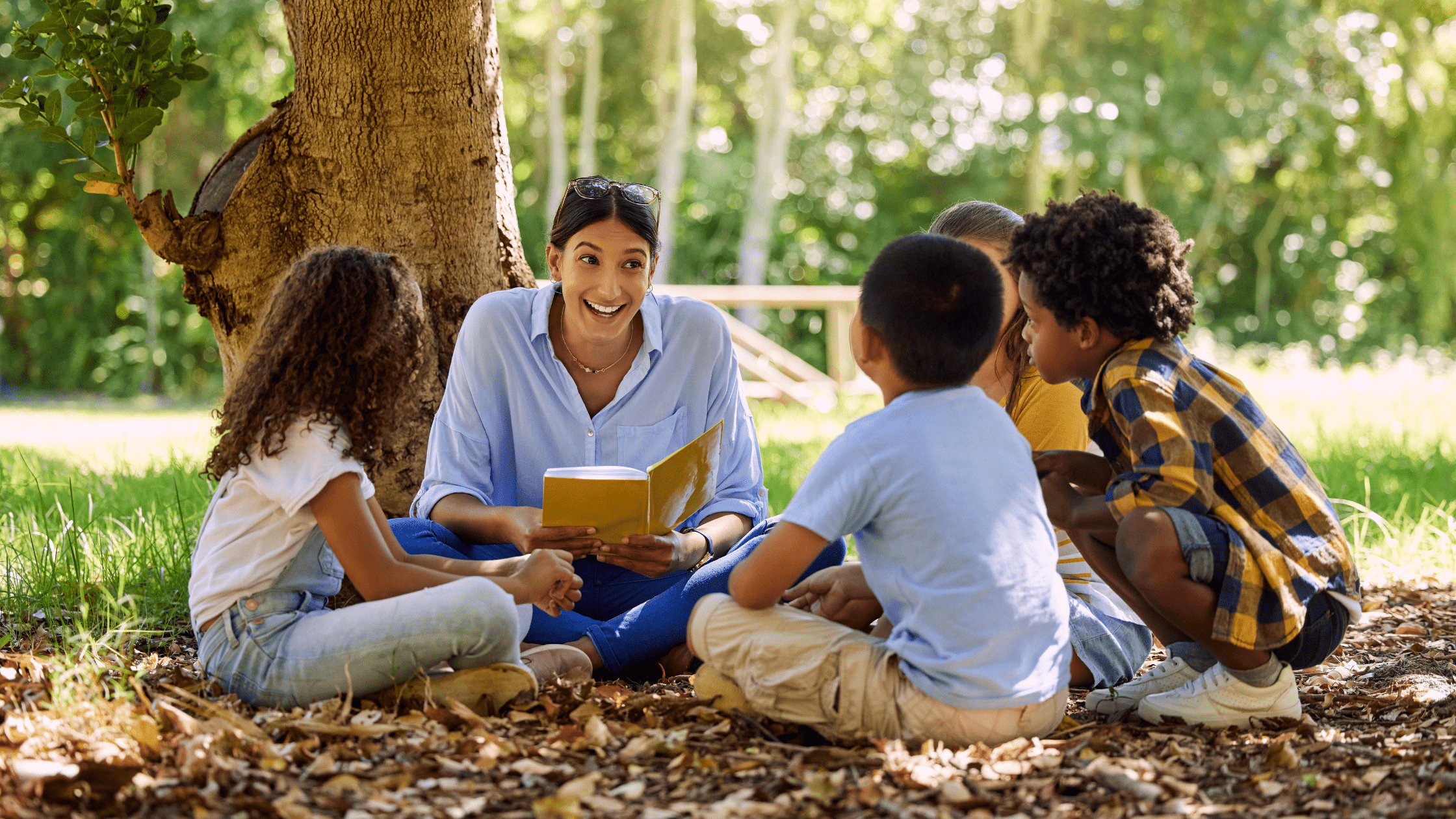 a teacher reading a book to a group of students outside