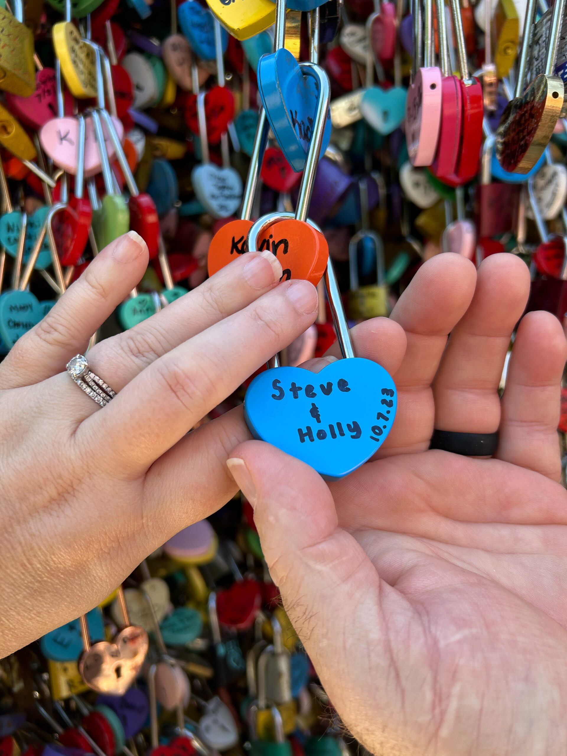 Couple holding their newly placed love lock among hundreds of colorful locks.
