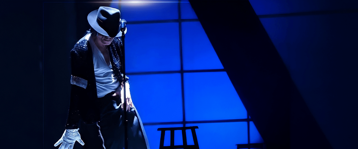 Performer wearing a white fedora, sequined jacket and white gloves at a microphone on a blue-lit stage.
