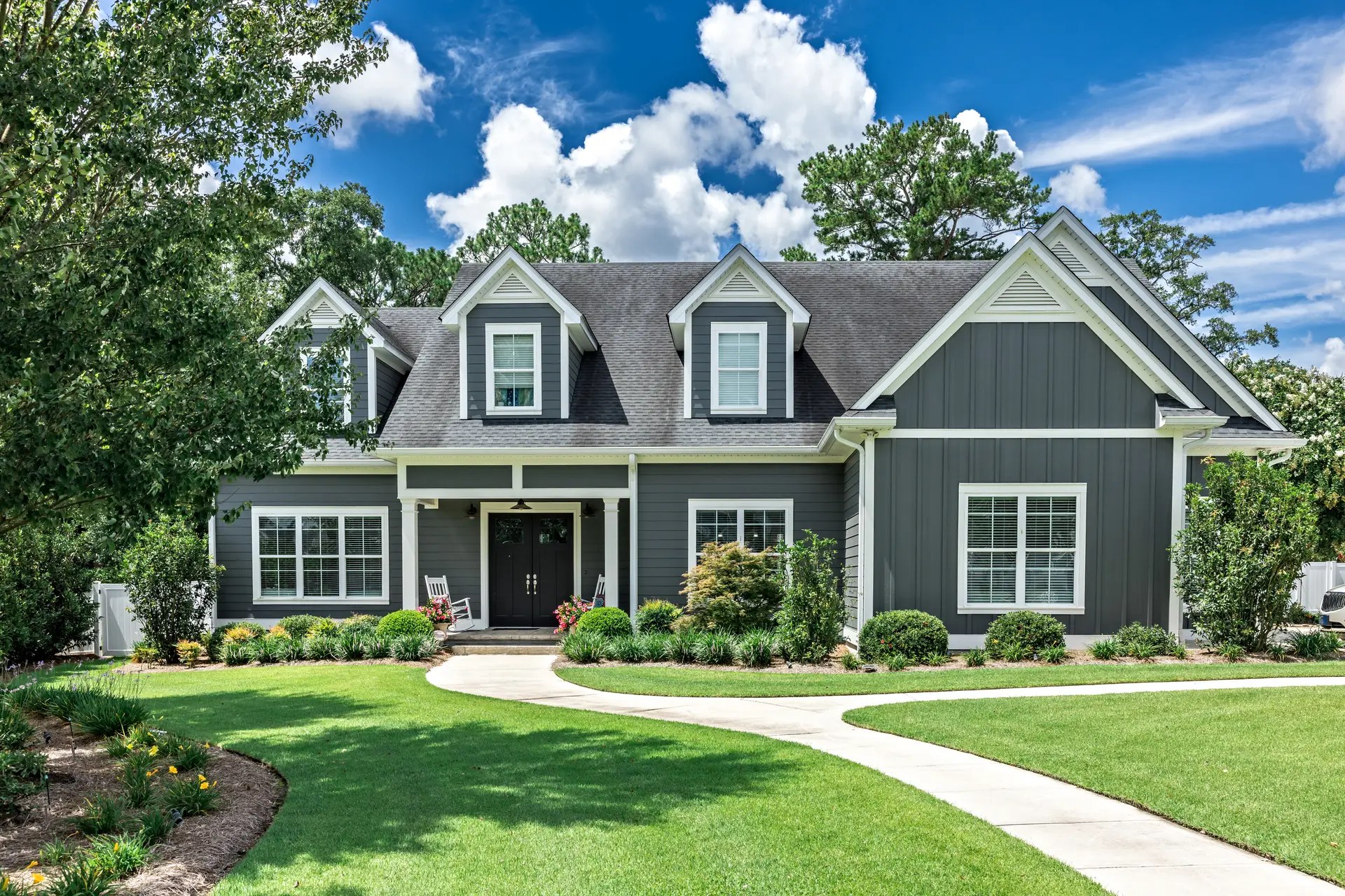 A large gray craftsman new construction house with a landscaped yard and leading pathway sidewalk - 0