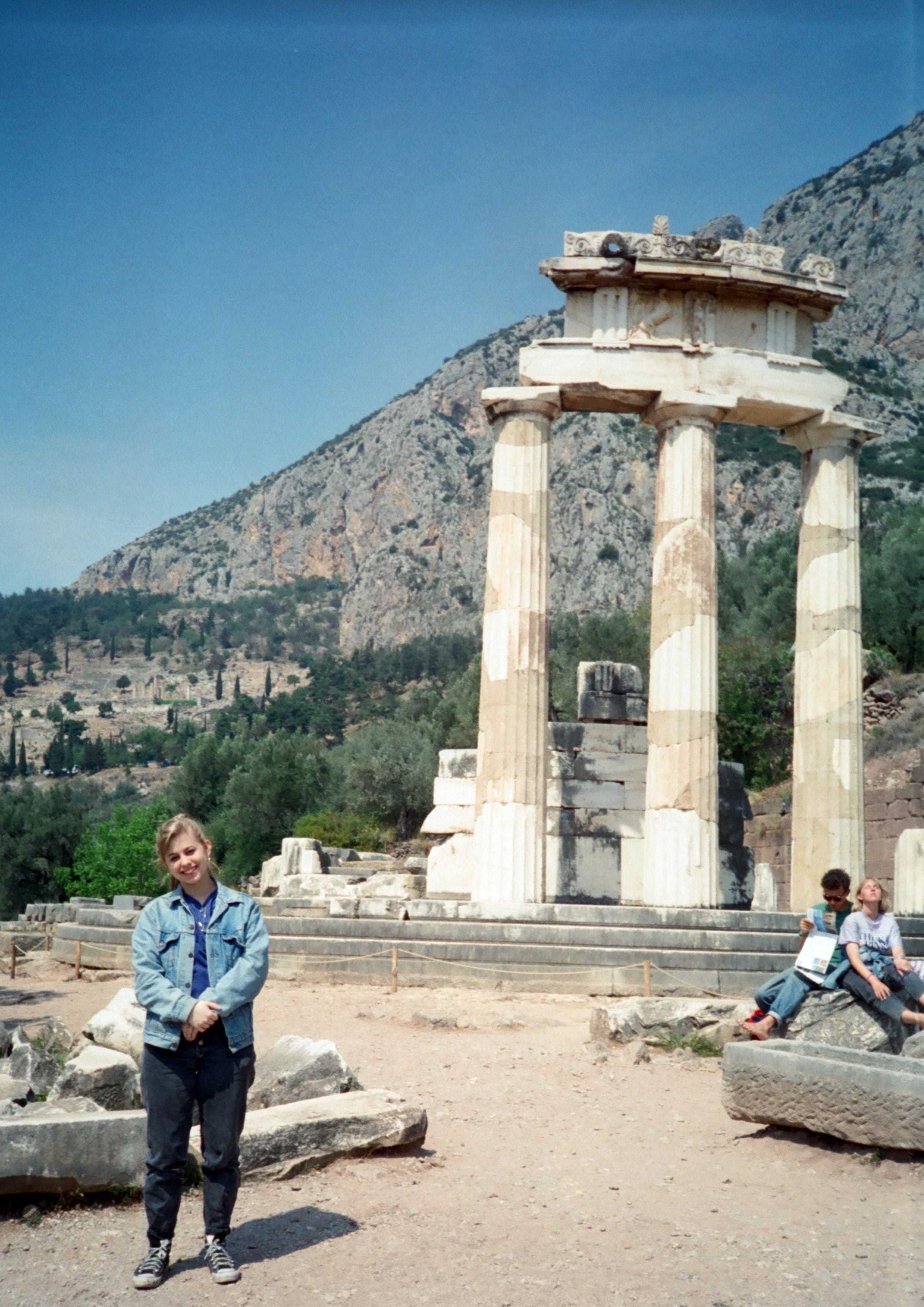 young woman standing in front of greek ruins