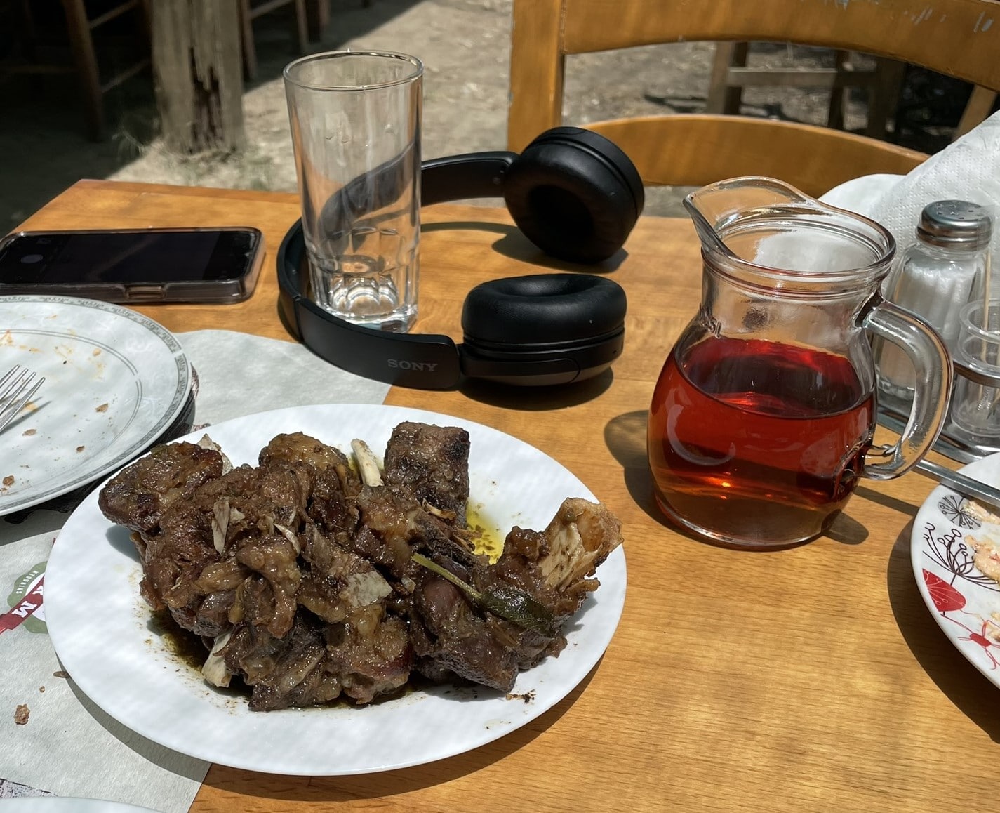 pitcher of wine next to a plate containing a browned meat dish