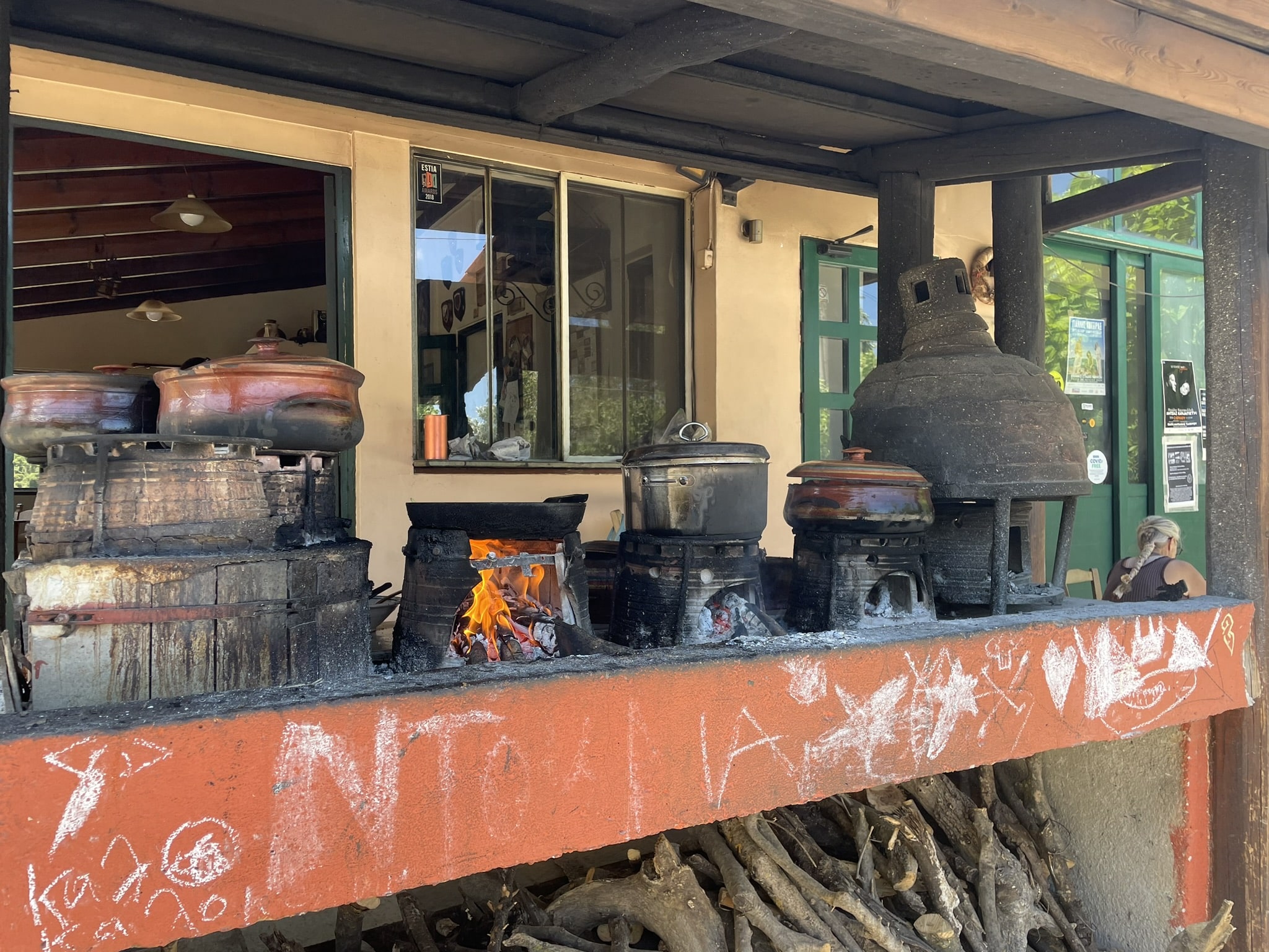 outdoor kitchen where several pots sit atop wood fires