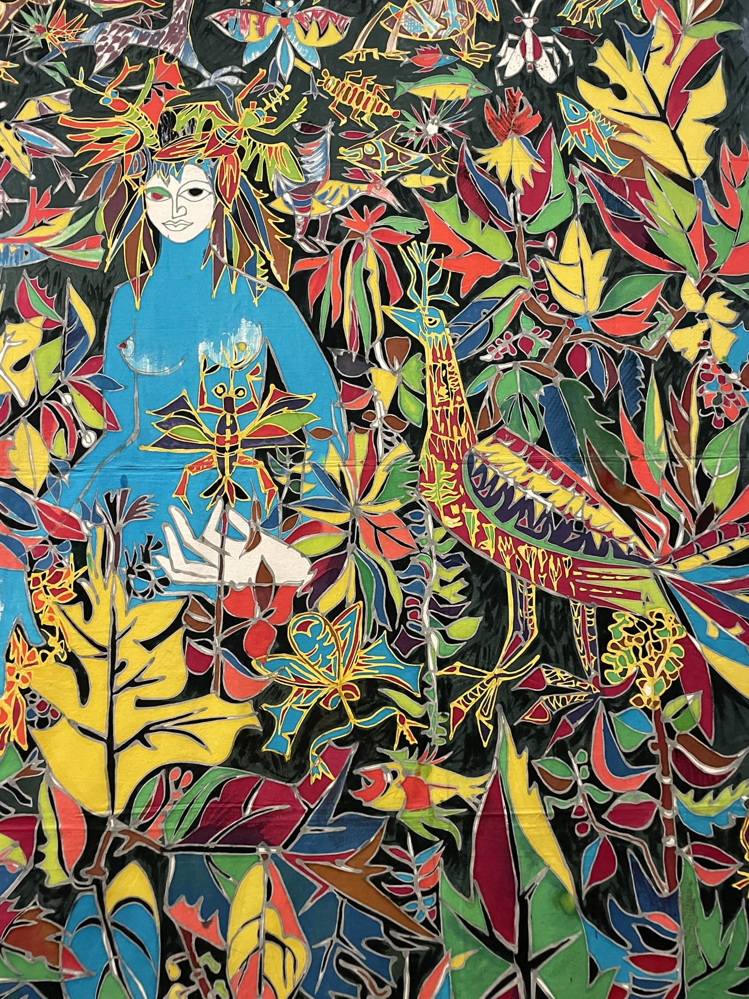Colorful depiction of a woman with a blue body and a white face sitting in a jungle setting surrounded by colorful leaves and creatures including a bird, fish, and some kind of insect