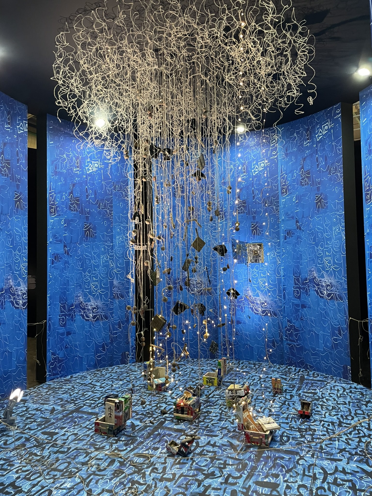 Circular room with blue walls, with a centerpiece of white tendrils handing form the ceiling