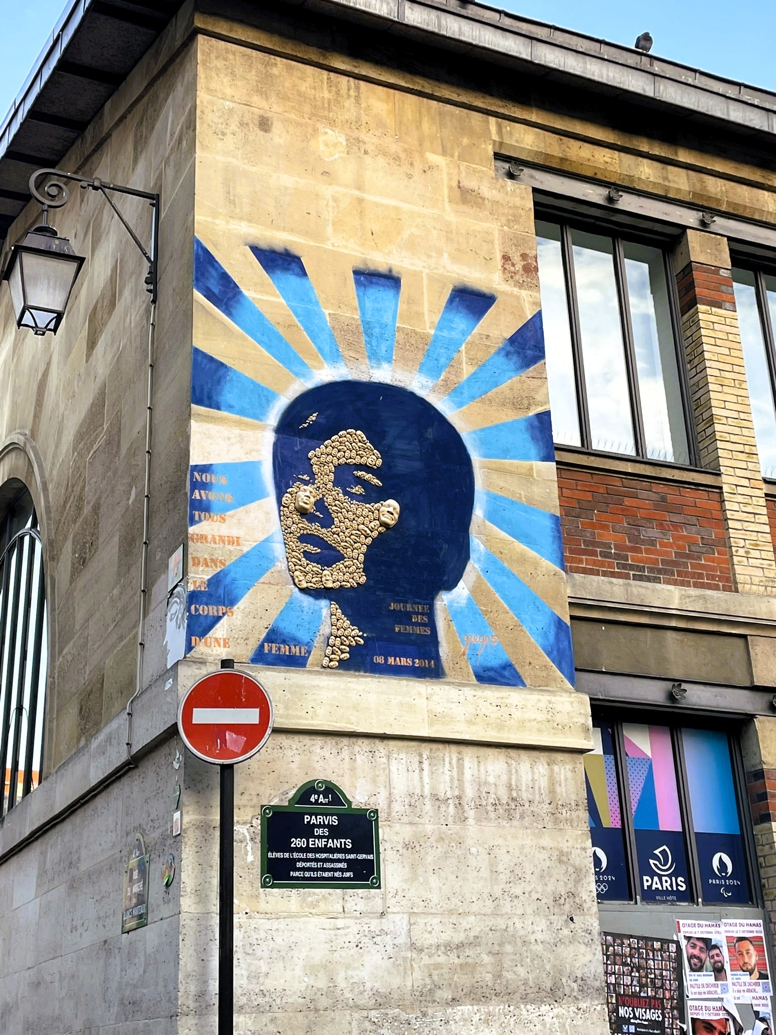 gold and blue street art of a women, above street sign for Le Parvis des 260-Enfants