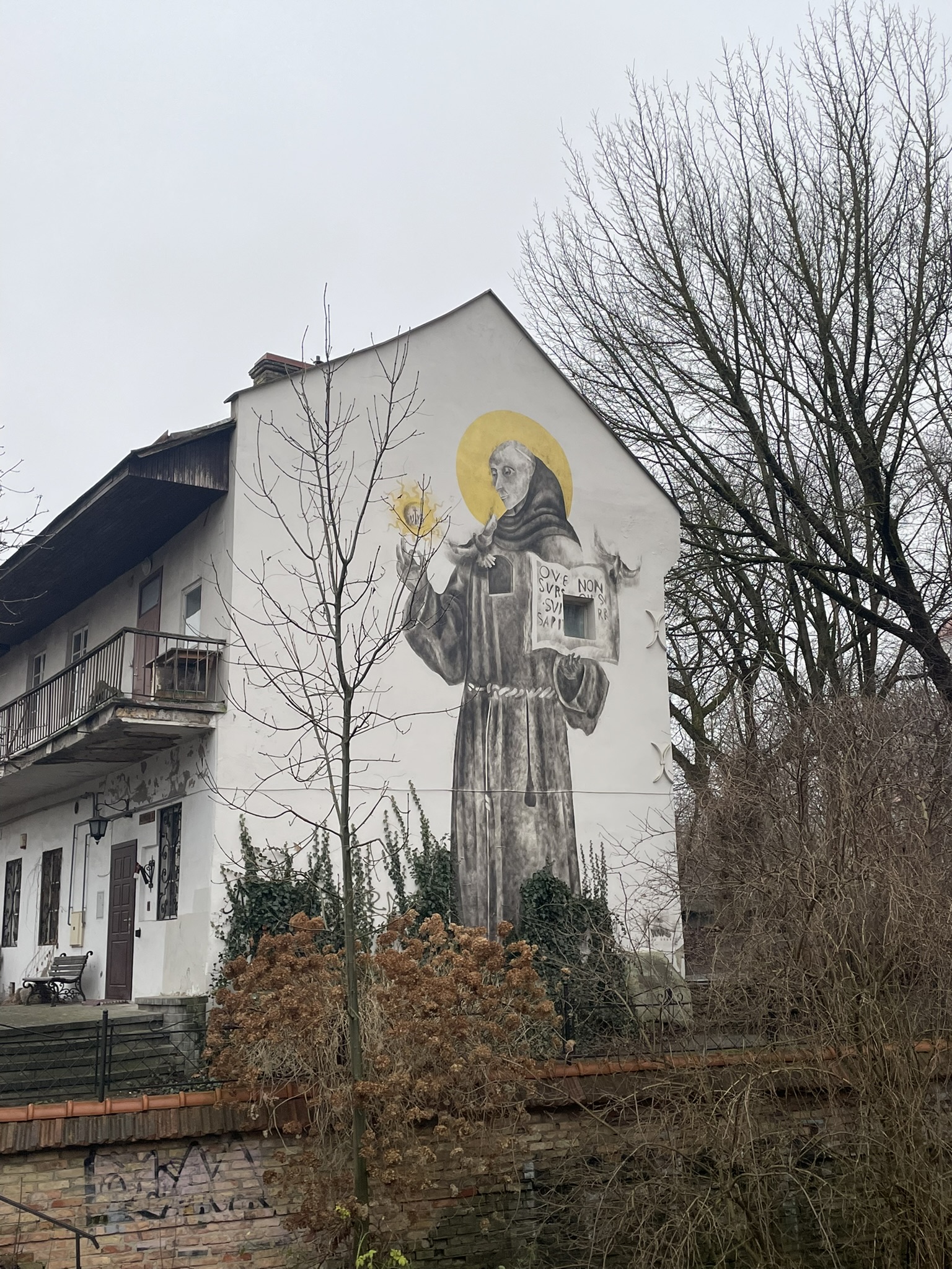 Two story building with a mural of a saint/monk painted on the side