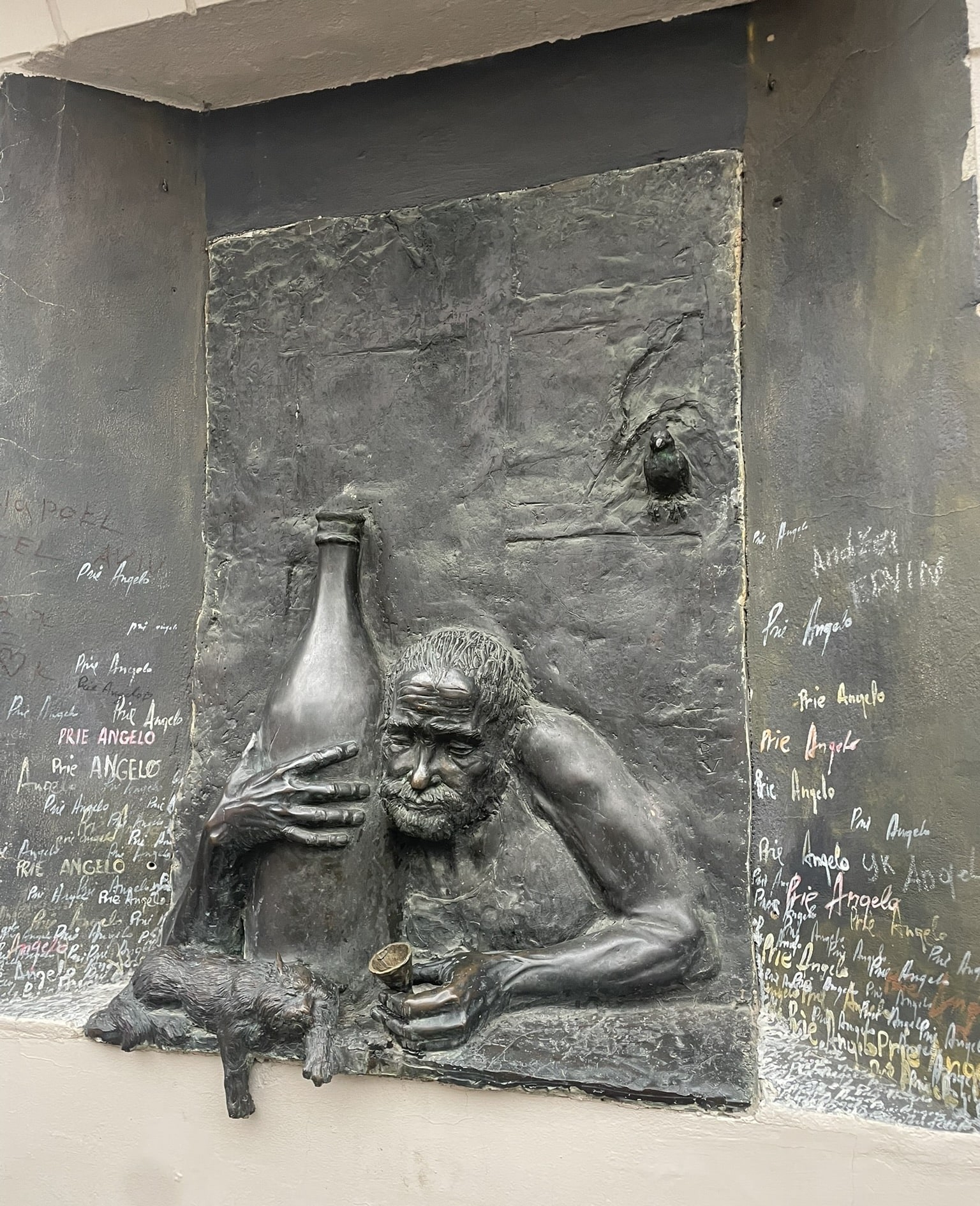 bas relief of a man hugging a giant bottle of wine