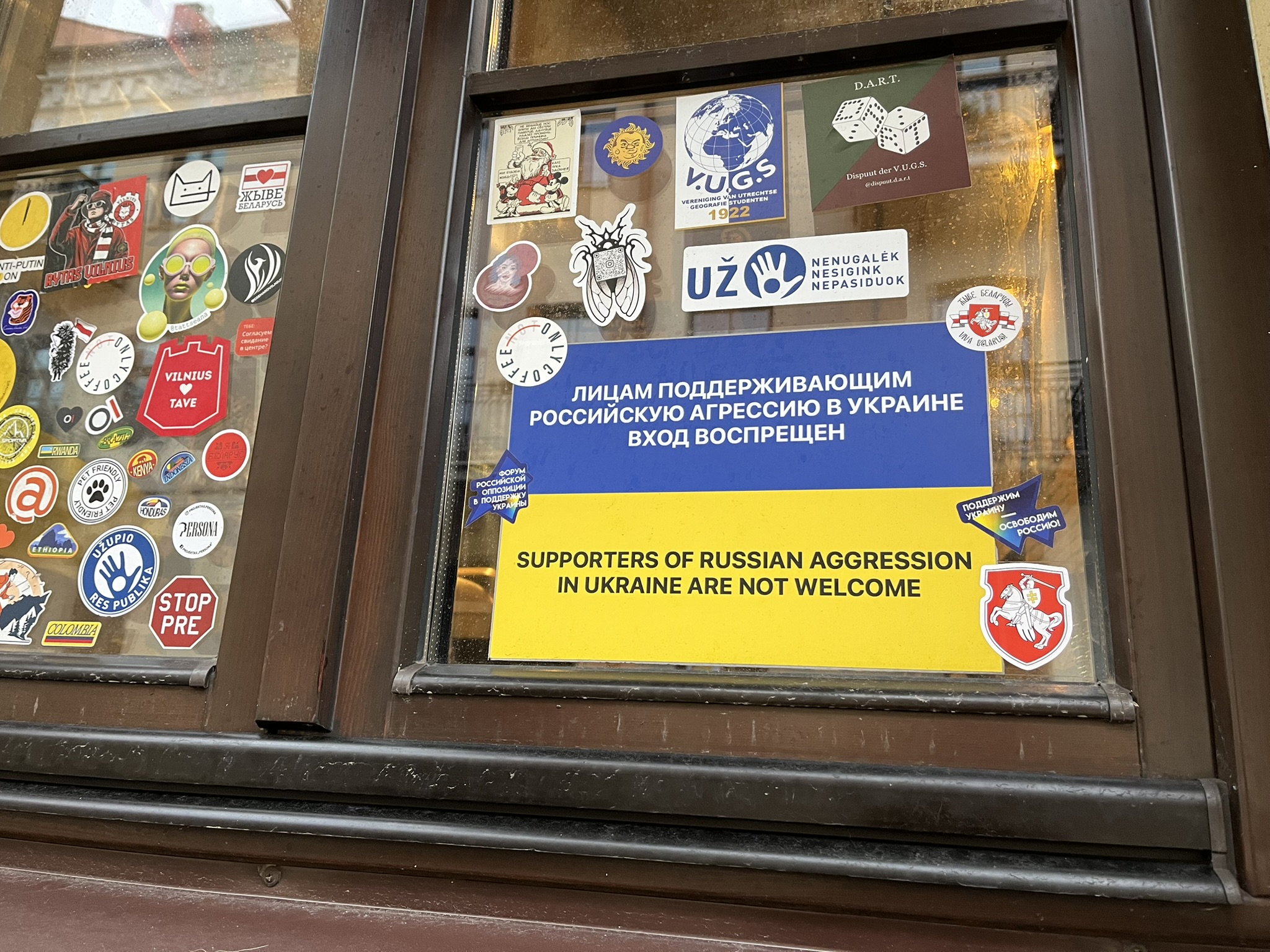 window plastered with several stickers including one that reads "supporters of Russian aggression Ukraine are not welcome"