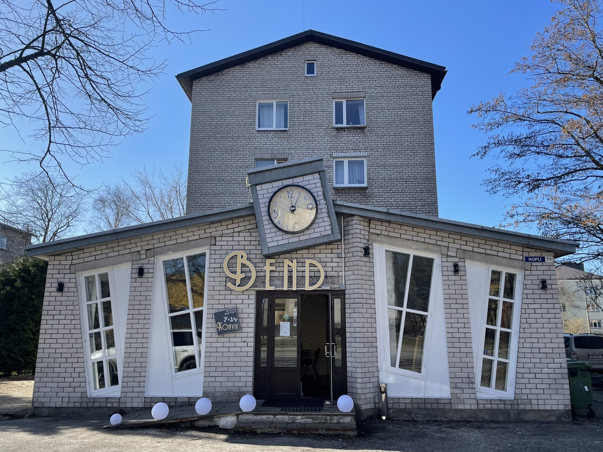 Storefront sign reading "Bend" set in a building with off kilter windows and an off kilter clock on the front
