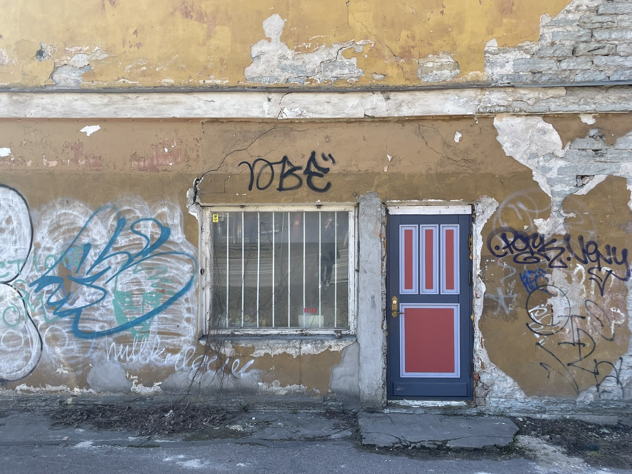 colorful red and gray doorway in a run down and graffitied cement building