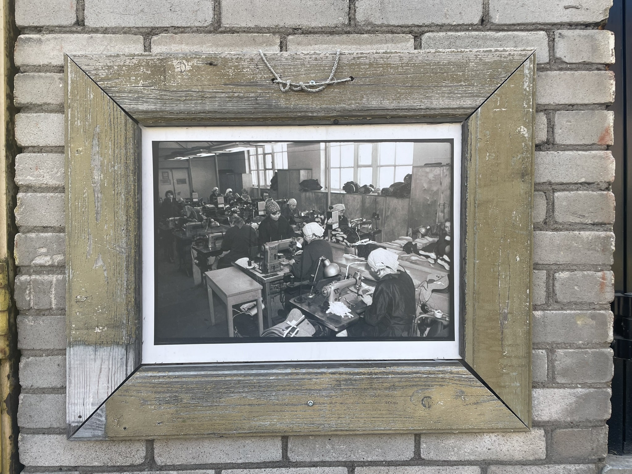 black and white framed photo of women sewing machines in a factory setting