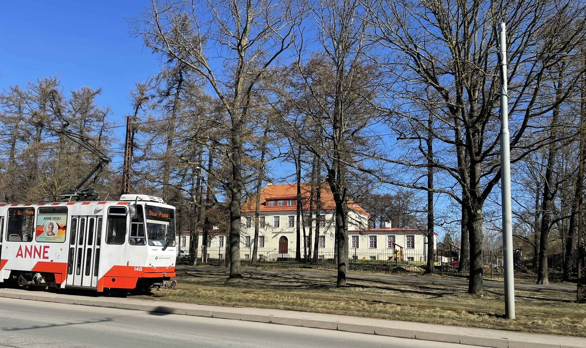 Stately white building in the background with a tram running in front