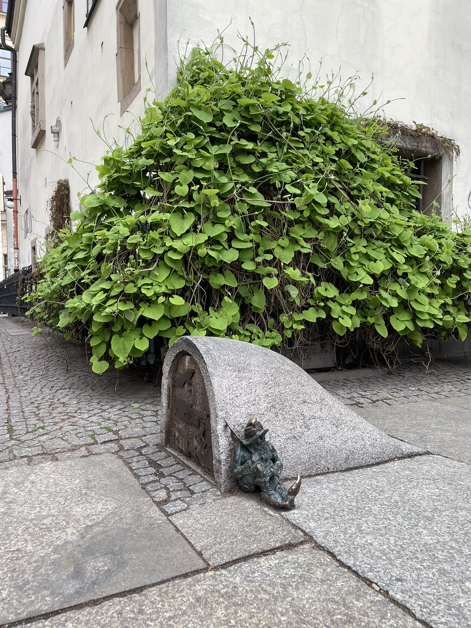 statue of s small gnome leaning against an arched entryway