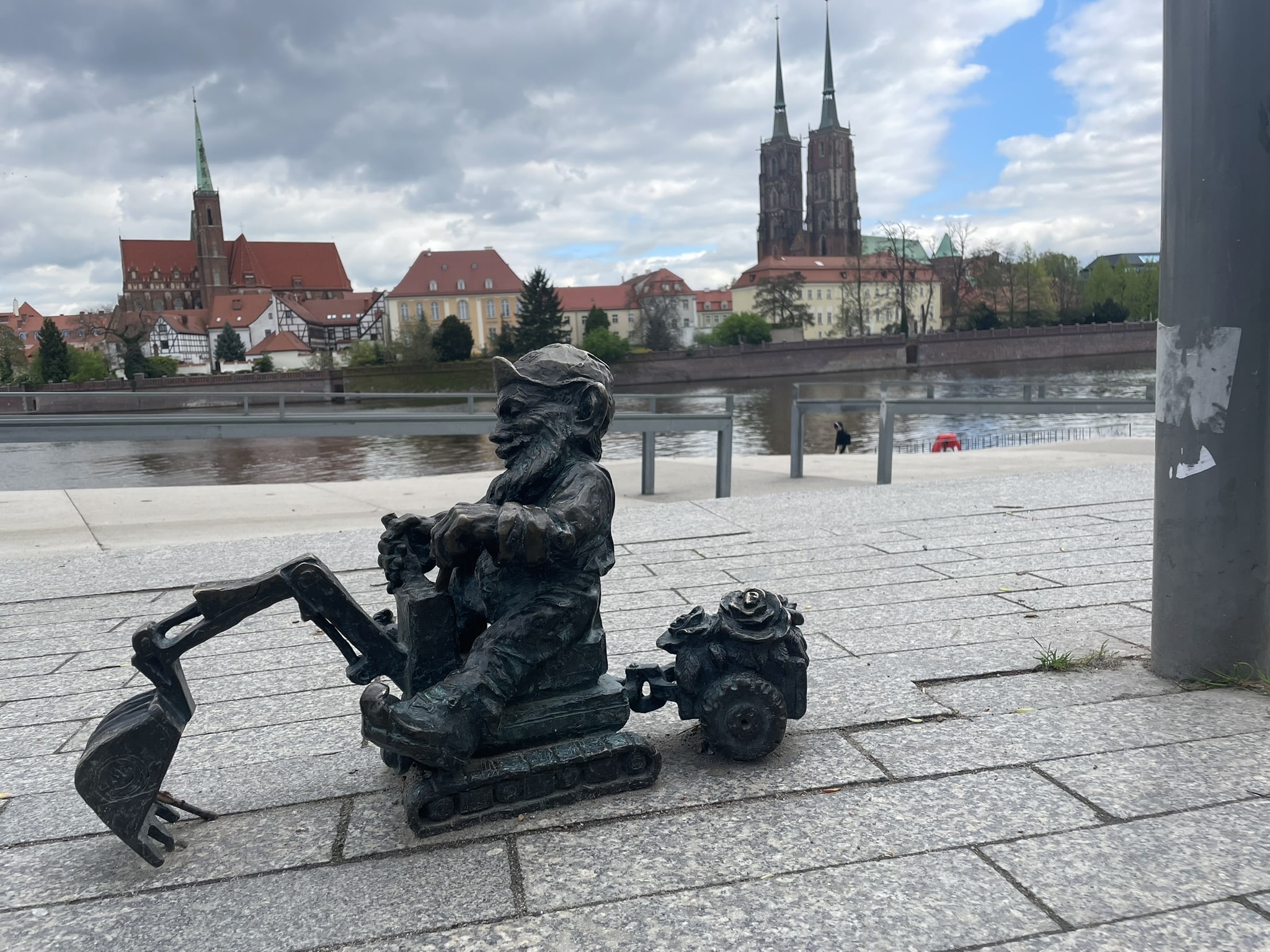 small statue of a gnome on an excavator, with church steeples seen in the background