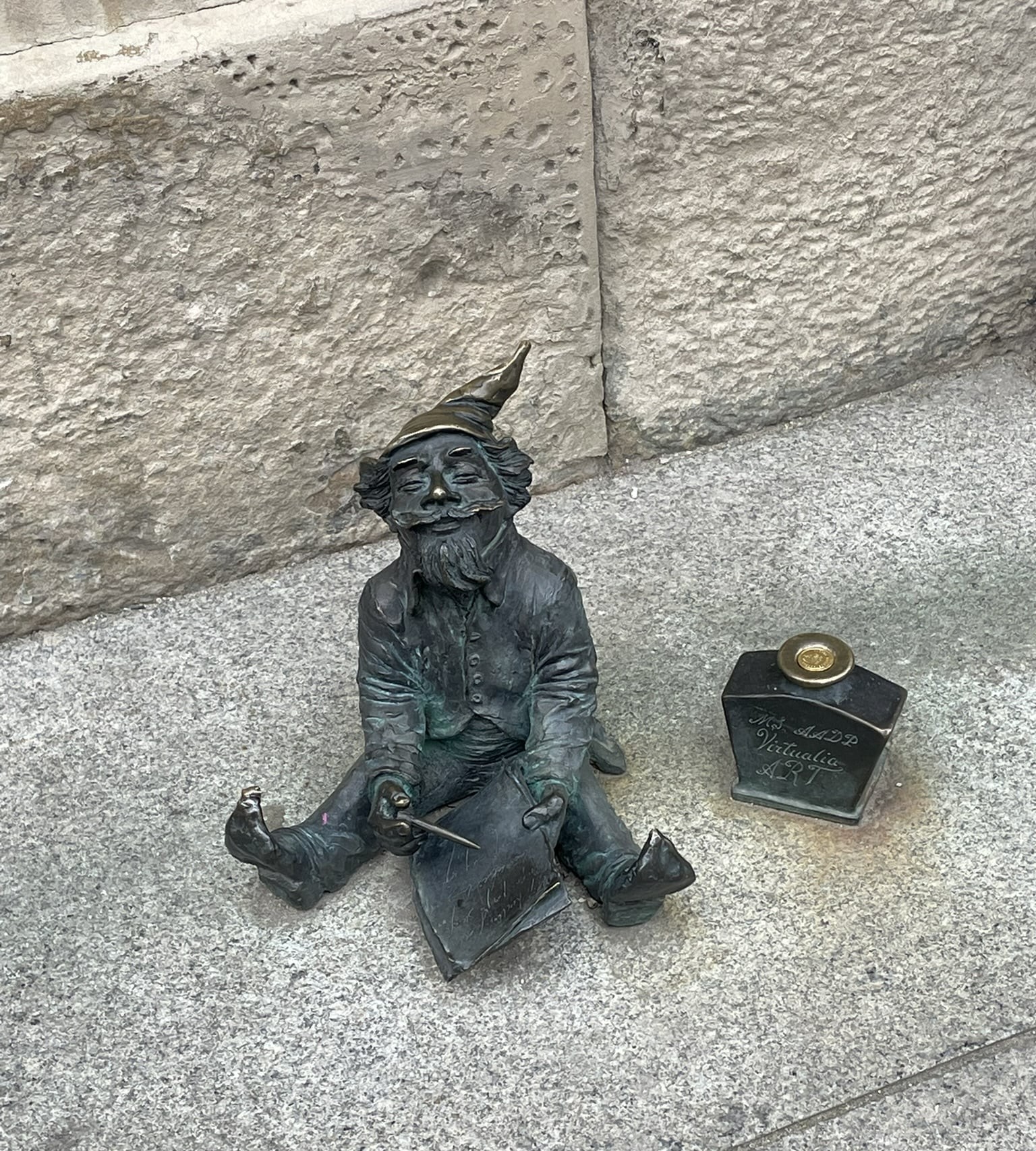 small statue of a gnome with a pen and bottle of ink
