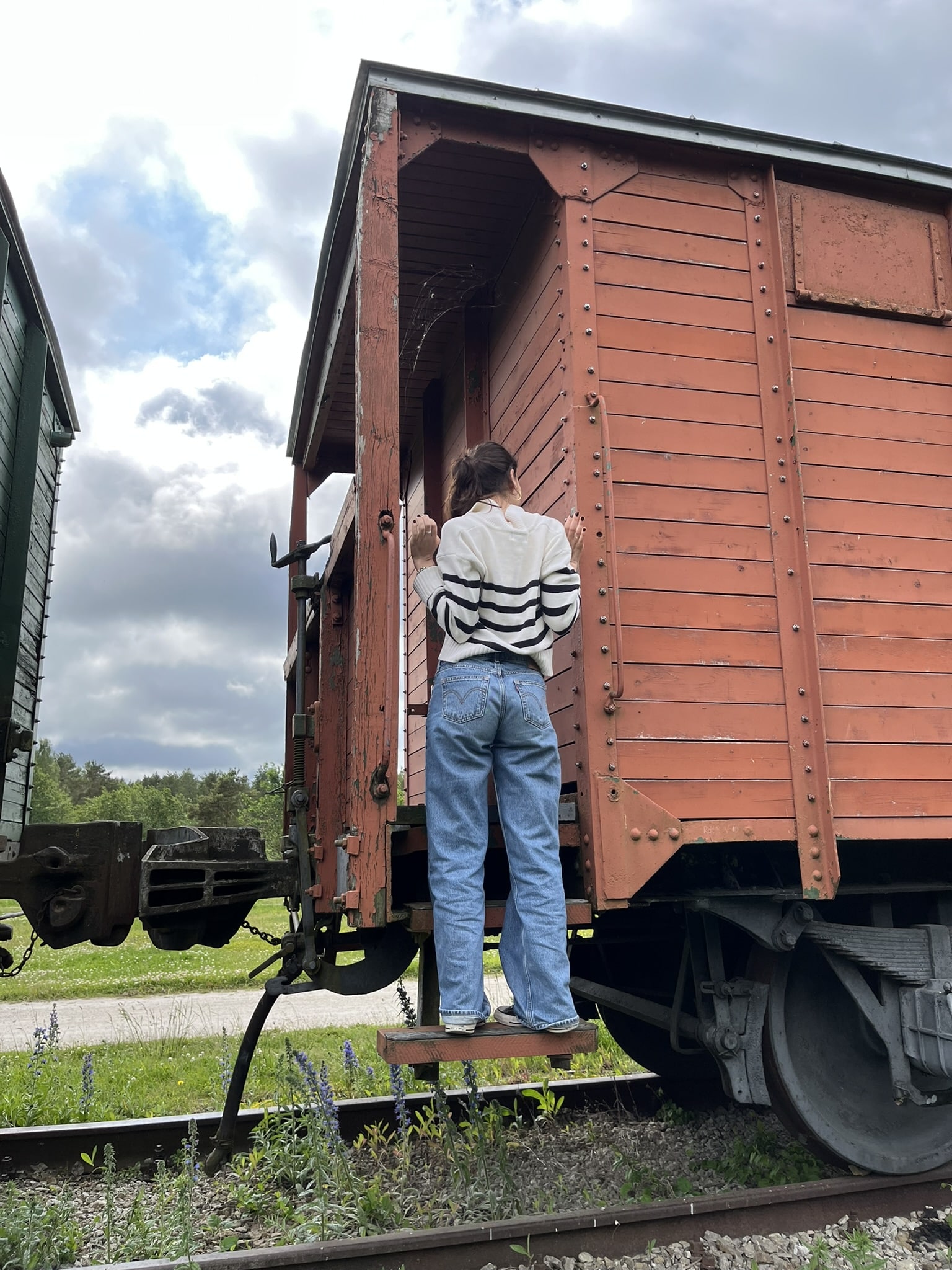 Woman with pong tail facing away from the camera and climbing on a train car