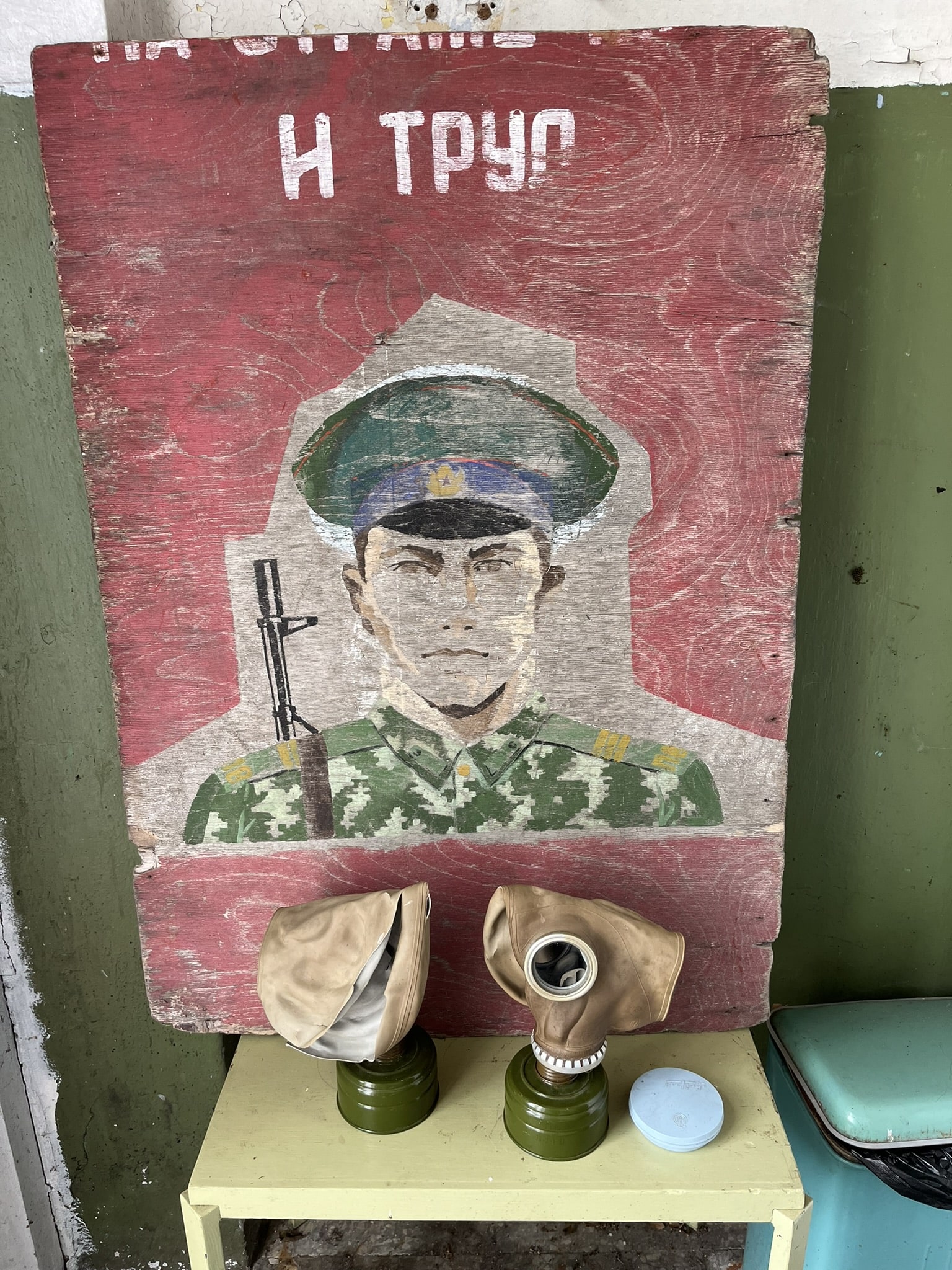 Painting on wood of a red background and a solider in the front, with some worn cyrillic letters above