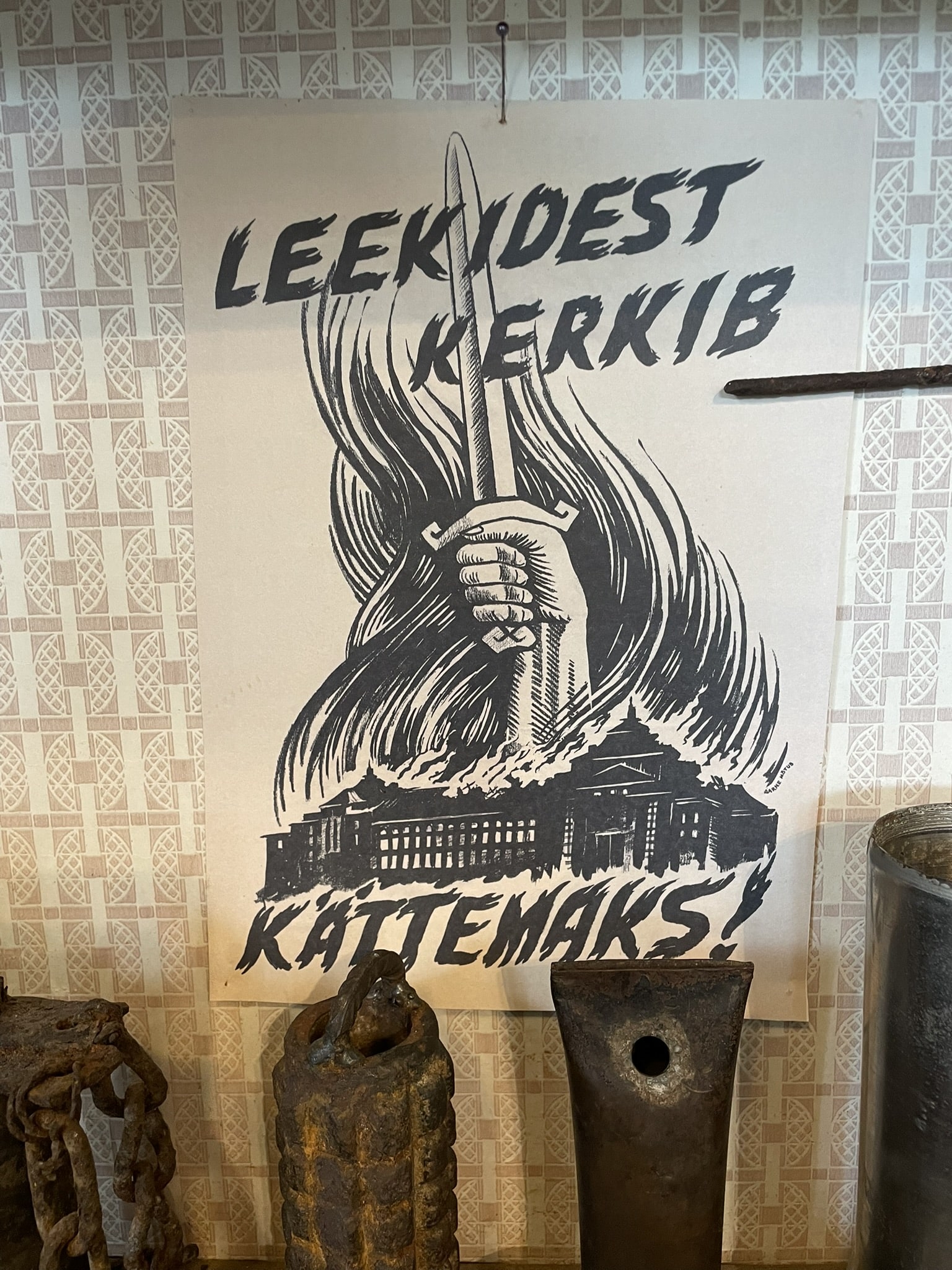 Poster of a hand clutching a sword over a building, reading Leekidest Kerkib Kattemaks!