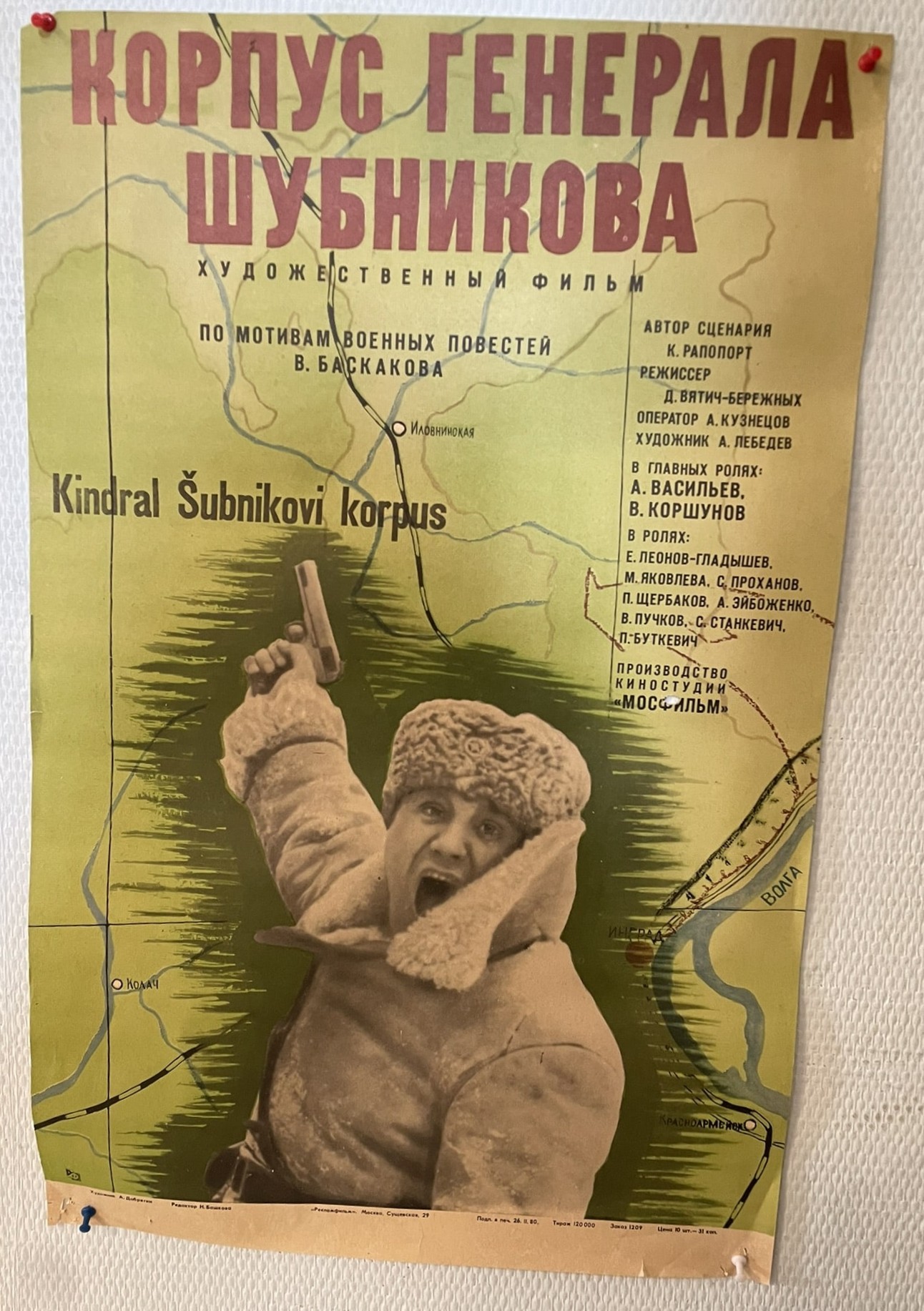 A yellow poster with cyrillic words and a picture of a man in winter weather clothes with a wide open mouth, pointing a gun in the air..