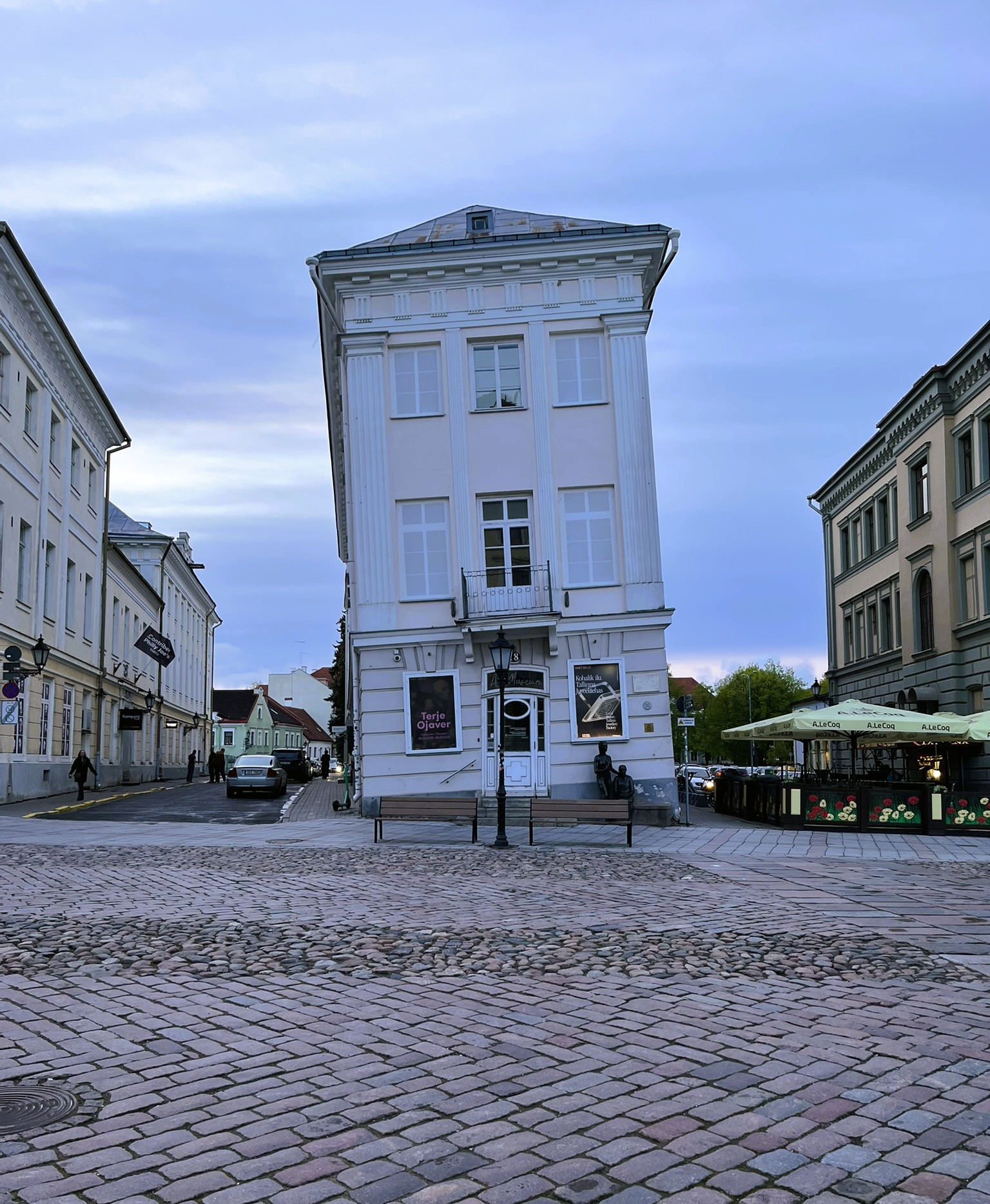 older building on a cobblestoned street, listing to the left.